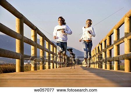 Couple Running With Their Dog View Large Photo Image Stock Photo - Couple Running With Their Dog. Fotosearch