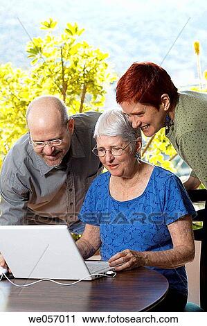 Stock Image - Elderly woman checks her email with her son and daughter. Fotosearch