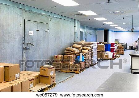 Stock Photo - Ingredients stacked next to a large freezer in a dessert factory. Fotosearch