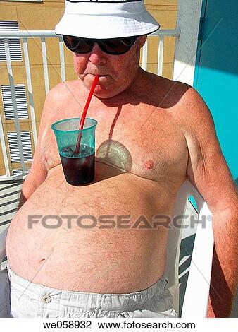 Stock Image - jElderly Man Sucking Drink Through a Straw From a Drink Sitting on His Stomach. Fotosearch