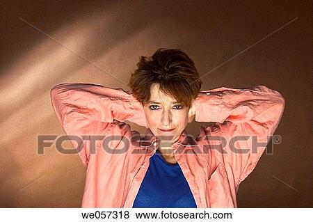 Stock Photo - Middle_age woman with her hands covering her ears. Fotosearch
