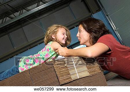 Mother and her young daughter posing together on a pile of cardboard boxes in a factory View Large Photo Image Stock Photo - Mother and her young daughter posing together on a pile of cardboard boxes in a factory. Fotosearch