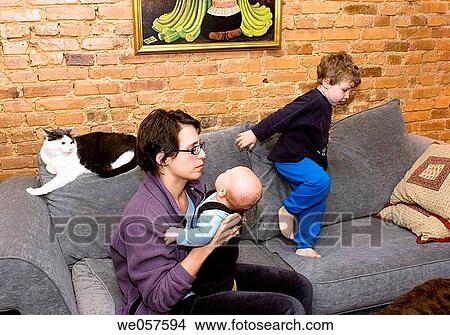 Mother with three_month old and three_year old playing on the couch while cat looks on. View Large Photo Image Picture - Mother with three_month old and three_year old playing on the couch while cat looks on.. Fotosearch