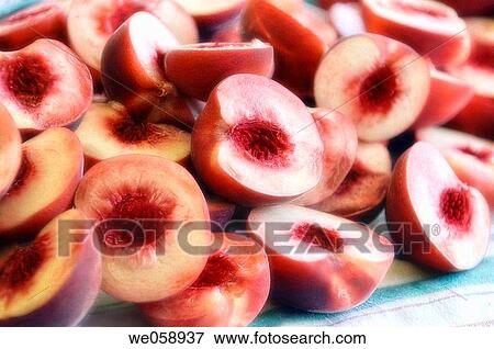Stock Photo - Peaches cut in halves (Prunus persica). August 2006, Maryland, USA. Fotosearch
