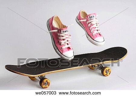 Stock Image - Pink shoes land on a skateboard. Fotosearch