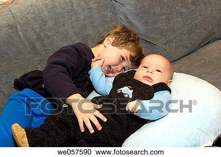 Three_month_old and three_year_old sitting on a couch View Large Photo Image Stock Image - Three_month_old and three_year_old sitting on a couch. Fotosearch