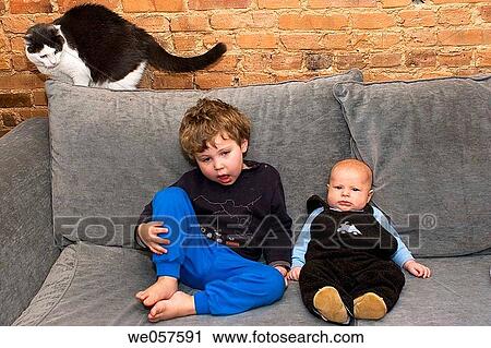 Three_year_old and three_month_old on the couch with cat looking on. View Large Photo Image Stock Image - Three_year_old and three_month_old on the couch with cat looking on.. Fotosearch