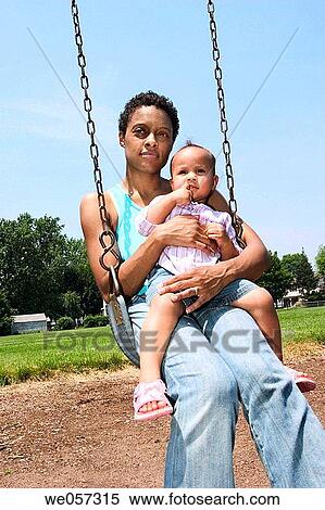 Young Hispanic mother and her Hispanic/Italian toddler daughter riding on a swing at a park View Large Photo Image Stock Photography - Young Hispanic mother and her Hispanic/Italian toddler daughter riding on a swing at a park. Fotosearch
