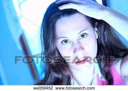 Stock Image - Young woman, her hand on her head, posing. Fotosearch
