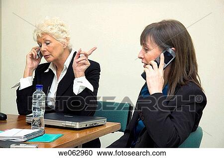 Businesswomen using mobile phones during a meeting. View Large Photo Image Stock Image - Businesswomen using mobile phones during a meeting.. Fotosearch
