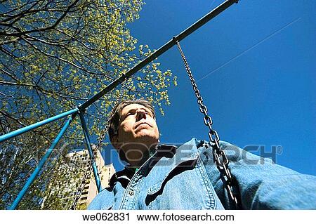 Close_up of a man sitting on a swing View Large Photo Image Stock Image - Close_up of a man sitting on a swing. Fotosearch