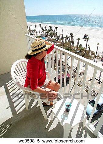 Elderly woman hanging onto hat on a windy day while sitting on a balcony View Large Photo Image Stock Photography - Elderly woman hanging onto hat on a windy day while sitting on a balcony. Fotosearch