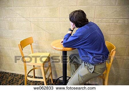 Man sitting at a table in a restaurant View Large Photo Image Stock Image - Man sitting at a table in a restaurant. Fotosearch