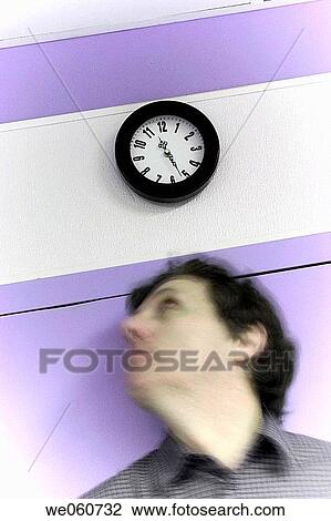 Middle_age man standing under a clock that is on a factory wall View Large Photo Image Stock Image - Middle_age man standing under a clock that is on a factory wall. Fotosearch