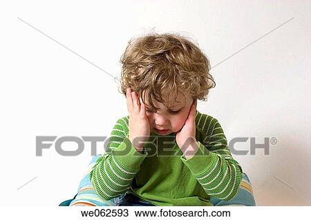 Stock Image - Three-year-old boy holding his head. Fotosearch