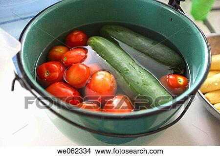 Picture - Tomato and cucumber in pot of water. Fotosearch
