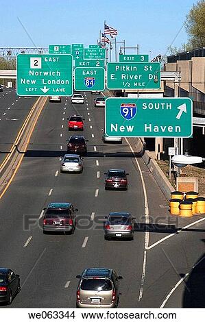 Picture - Traffic signs and automobiles on a stretch of highway going through a city.. Fotosearch
