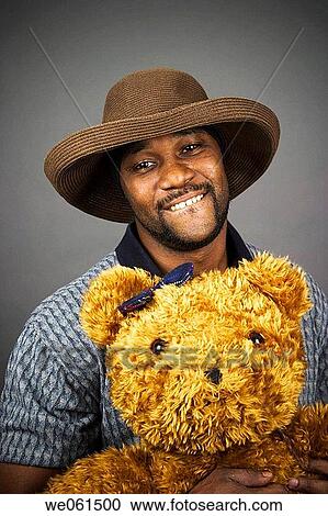 Young black man wearing a hat and holding a stuffed animal View Large Photo Image Stock Image - Young black man wearing a hat and holding a stuffed animal. Fotosearch