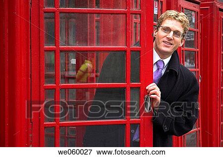 Young businessman leaning out of a British red phone box. View Large Photo Image Stock Photo - Young businessman leaning out of a British red phone box.. Fotosearch