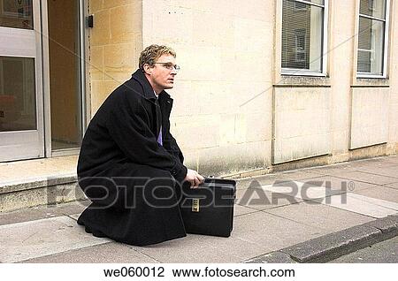 Young businessman outside office kneeling to look in his briefcase. Shot in Bath, United Kingdom. View Large Photo Image Stock Image - Young businessman outside office kneeling to look in his briefcase. Shot in Bath, United Kingdom.. Fotosearch