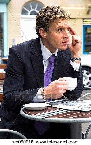 Stock Photo - Young businessman sitting outside at a cafe with a newspaper. Shot in Bath, United Kingdom.. Fotosearch