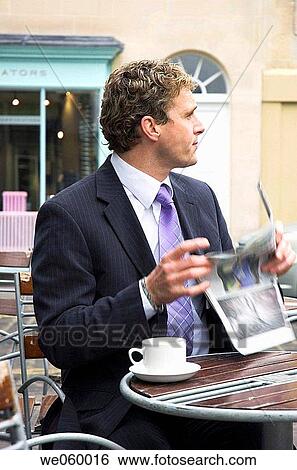 Young businessman sitting outside at a cafe with a newspaper. Shot in Bath, United Kingdom. View Large Photo Image Stock Photograph - Young businessman sitting outside at a cafe with a newspaper. Shot in Bath, United Kingdom.. Fotosearch
