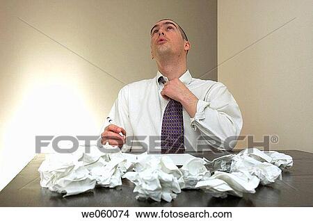 Young businessman struggling with some paperwork and expressing frustration in his body language. View Large Photo Image Picture - Young businessman struggling with some paperwork and expressing frustration in his body language.. Fotosearch