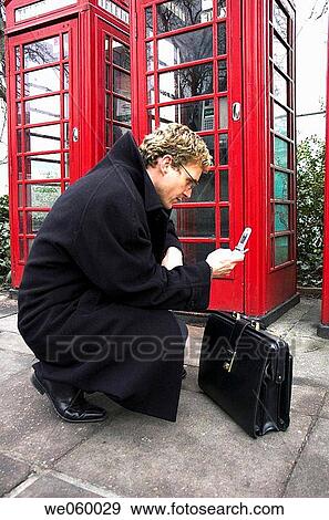 Young businessman talking on a mobile phone next to a row of British red phone boxes. View Large Photo Image Stock Photo - Young businessman talking on a mobile phone next to a row of British red phone boxes.. Fotosearch