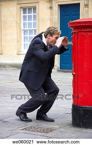 Young businessman trying to llok into a British Royal Mail post box. View Large Photo Image Stock Image - Young businessman trying to llok into a British Royal Mail post box.. Fotosearch