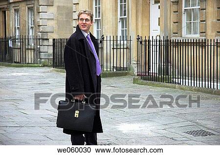 Stock Image - Young businessman walking with briefcase. Classic Georgian street surroundings. Shot in Bath, UK.. Fotosearch