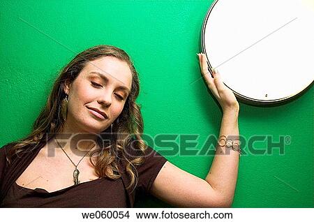 Picture - Young female fashion model posing against wall mounted light.. Fotosearch