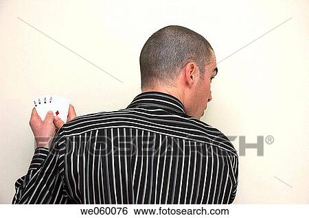 Young man glances over his shoulder while shielding a playing card hand of four aces. View Large Photo Image Stock Photograph - Young man glances over his shoulder while shielding a playing card hand of four aces.. Fotosearch