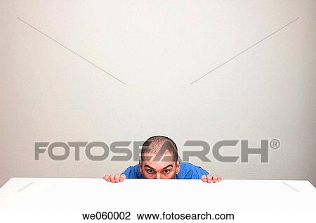 Young man in business shirt peaking over the edge of a clear desk. Body language suggests nervousness. View Large Photo Image Stock Image - Young man in business shirt peaking over the edge of a clear desk. Body language suggests nervousness.. Fotosearch
