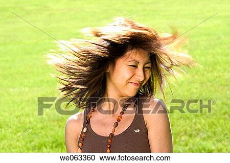 Stock Image - Young Spanish/Asian woman shaking her head while posing at a park.. Fotosearch