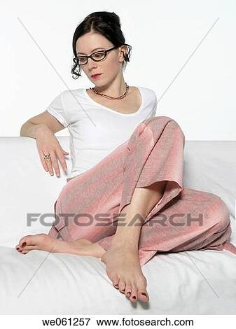 Young woman is sitting on a sofa View Large Photo Image Stock Photo - Young woman is sitting on a sofa. Fotosearch