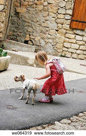3 year old girl bending down to strke a dog in the road View Large Photo Image Stock Photo - 3 year old girl bending down to strke a dog in the road. Fotosearch
