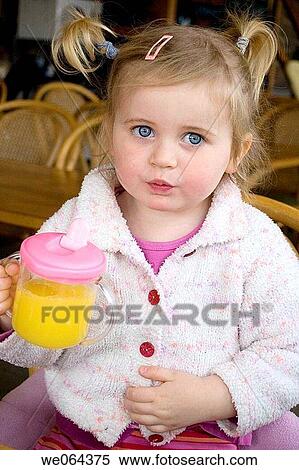 Stock Photography - 3 year old girl sitting drinking juice. Fotosearch