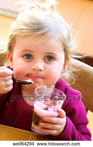 3 year old girl sitting eating a desert, licking her lips View Large Photo Image Picture - 3 year old girl sitting eating a desert, licking her lips. Fotosearch