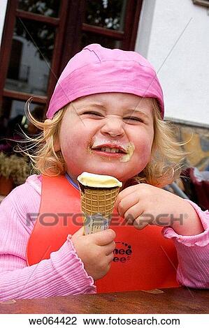 3 Year old girl sitting eating an ice cream with it all over her face pulling a face into camera View Large Photo Image Stock Image - 3 Year old girl sitting eating an ice cream with it all over her face pulling a face into camera. Fotosearch