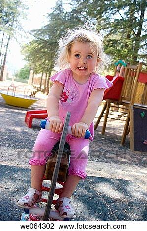 3 year old girl sitting on a rocking horse in the park View Large Photo Image Stock Image - 3 year old girl sitting on a rocking horse in the park. Fotosearch