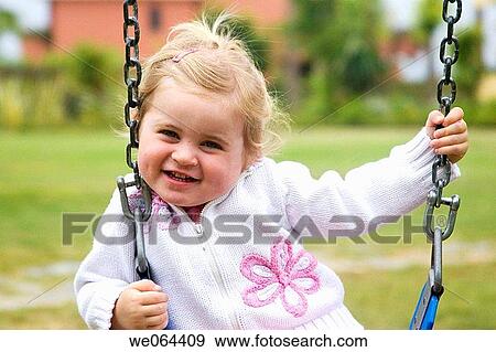 3 year old girl sitting on a swing smling into camera View Large Photo Image Stock Photo - 3 year old girl sitting on a swing smling into camera. Fotosearch