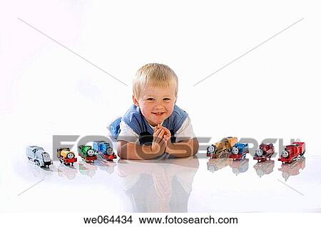 3Year old boy lying on his tummy on the studio floor, with his toy trains, smiling into camera View Large Photo Image Picture - 3Year old boy lying on his tummy on the studio floor, with his toy trains, smiling into camera. Fotosearch