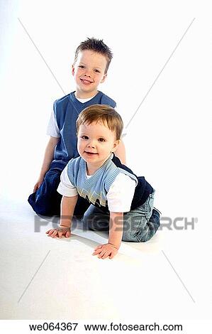 4 year old boysitting on the studio floor smiling into camera, with his one year old brother View Large Photo Image Stock Photo - 4 year old boysitting on the studio floor smiling into camera, with his one year old brother. Fotosearch