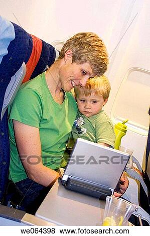 40 year old woman, on an aeroplane with her 3 yrear old boy, watching a dvd player View Large Photo Image Stock Photo - 40 year old woman, on an aeroplane with her 3 yrear old boy, watching a dvd player. Fotosearch