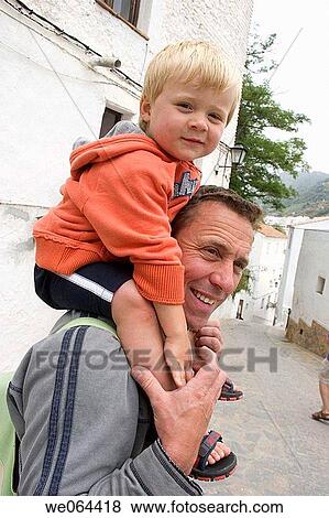 Stock Photo - 40_ 50 year old man with his son on his shoulders, smiling. Fotosearch