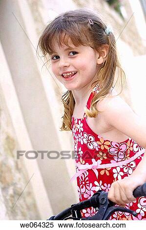 Stock Photography - 5 year old girl standing smiling into camera with her bike. Fotosearch