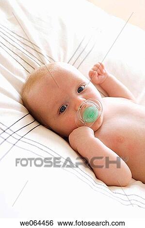 8 week old baby, sucking a dummy, gazing into camera, lying on the bed View Large Photo Image Stock Photograph - 8 week old baby, sucking a dummy, gazing into camera, lying on the bed. Fotosearch