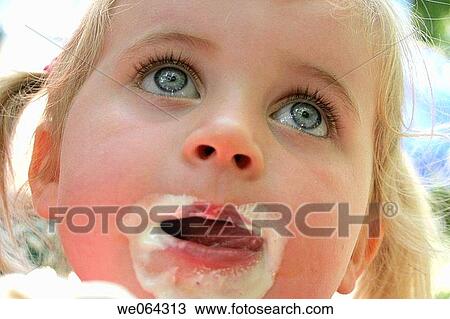 Stock Image - close up headshot of a 3 year old girl with ice cream all round her mouth. Fotosearch