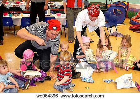 Stock Photograph - group of chidren playing pass the parcel, at a childrens pirate party, with the dads supervising. Fotosearch