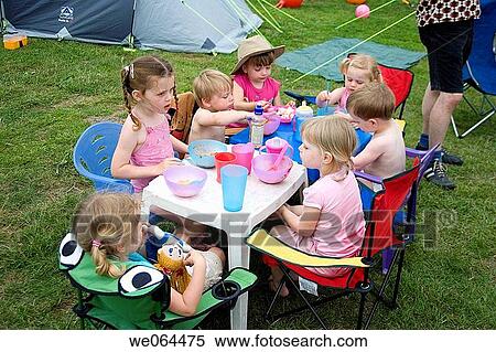 group of children sitting round a table eating tea on a camping trip View Large Photo Image Stock Photography - group of children sitting round a table eating tea on a camping trip. Fotosearch
